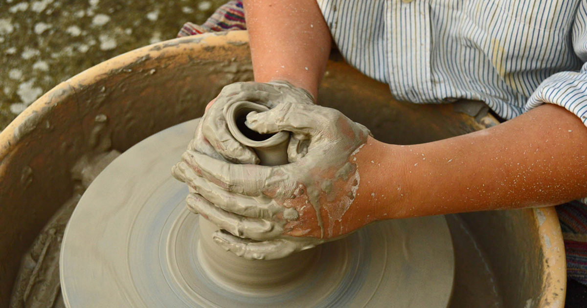 Hands shaping clay on a potter’s wheel during the pottery team building